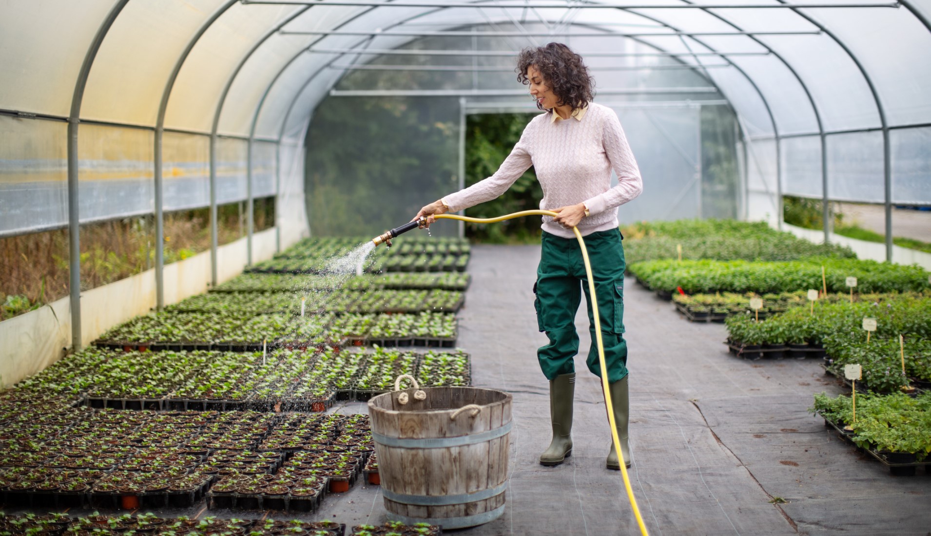 a woman with bipolar disorder at work watering plants in a greenhouse