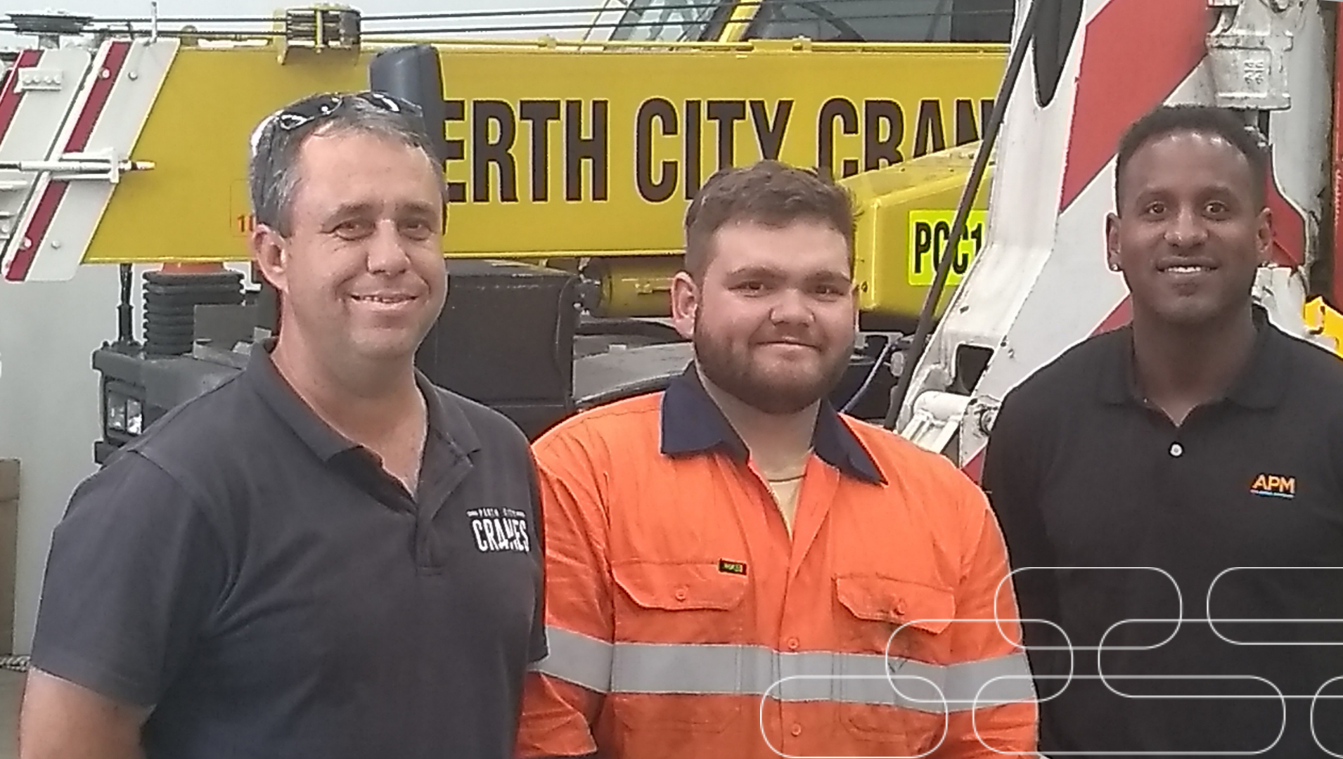 Jake stands in his hi-vis work uniform next to his boss and his APM consultant