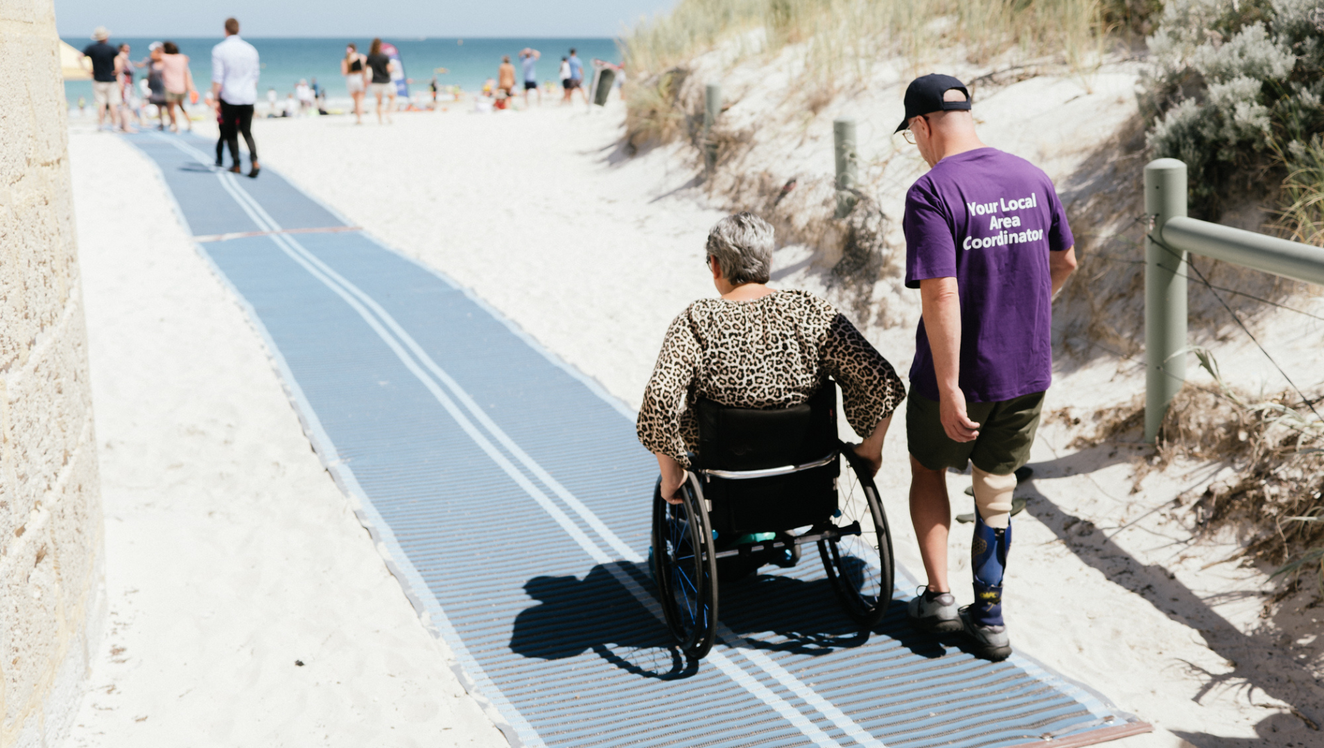 A wheelchair user on an accessible beach mat with APM Communities