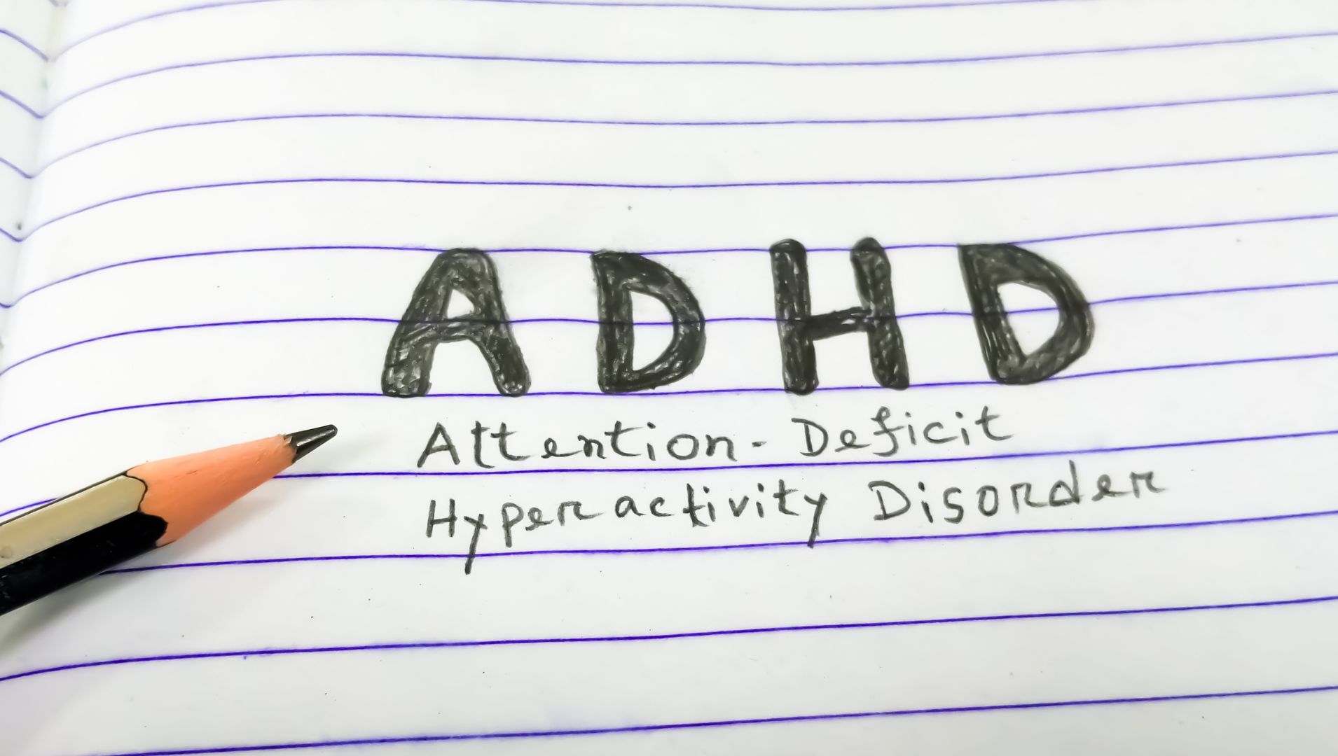 ADHD written on a page with a pencil
