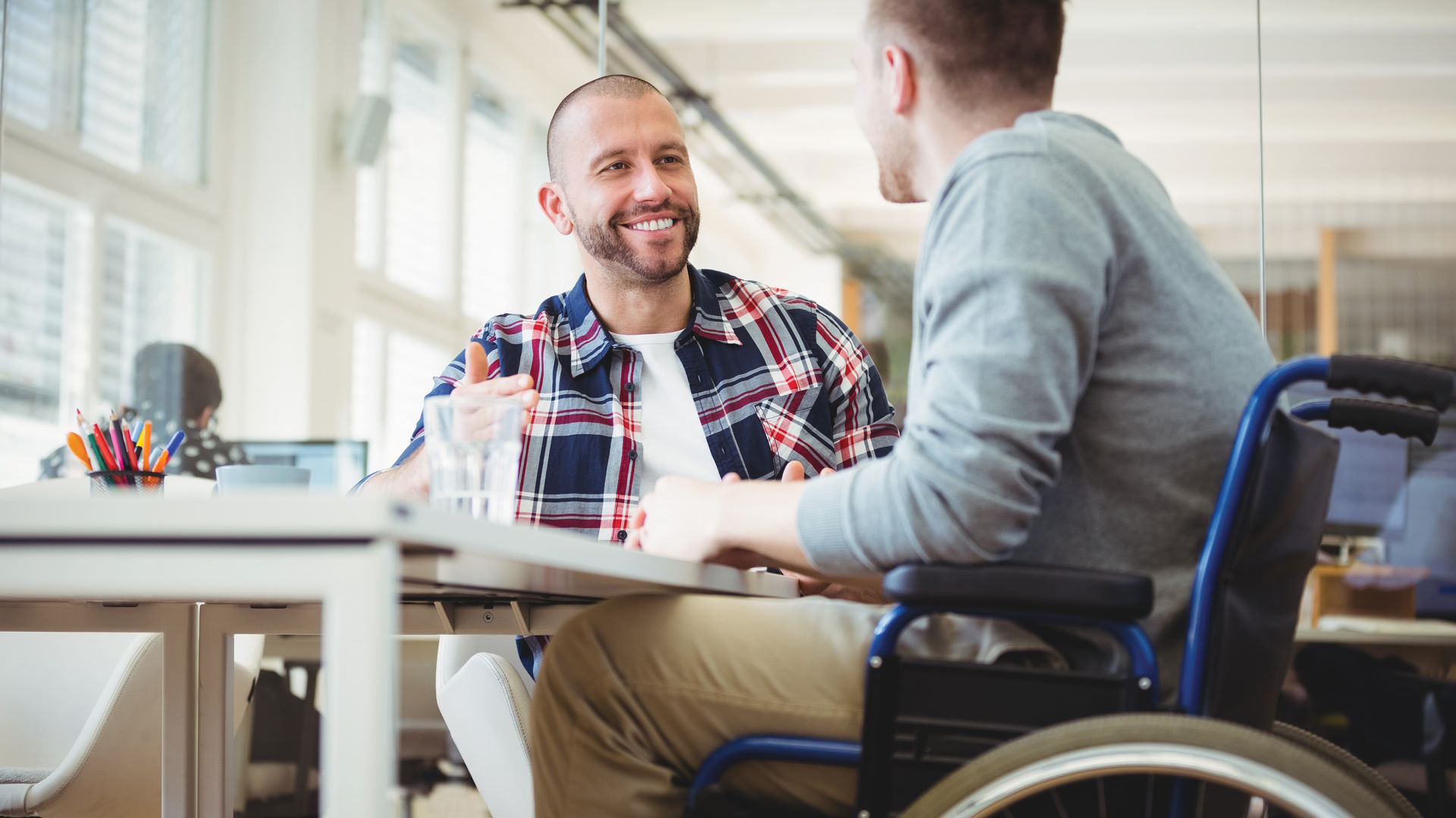 two men discussing, one in a wheelchair